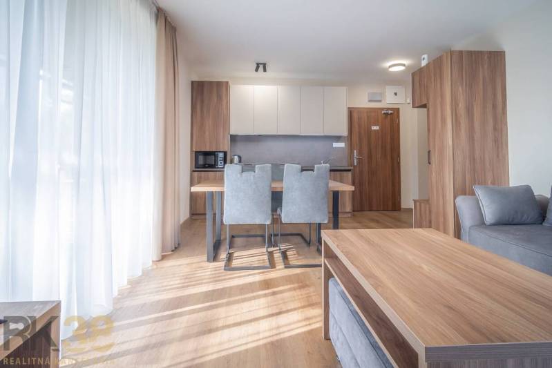 Lukratívne dvoj a štvorizbové byty v Tatranskej Lomnici na prenájom - Interiér 2-izbového bytu s kuchynským kútom, šedými stoličkami a podlahou s dreveným dekorom.
