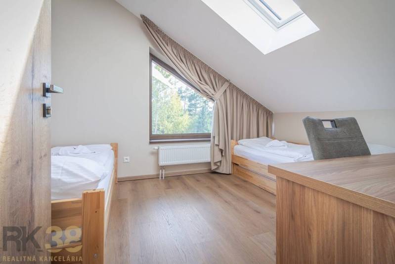 Lukratívne dvoj a štvorizbové byty v Tatranskej Lomnici na prenájom - Spálňa v 2-izbovom byte s dvomi posteľami a podlahou s dreveným dekorom.