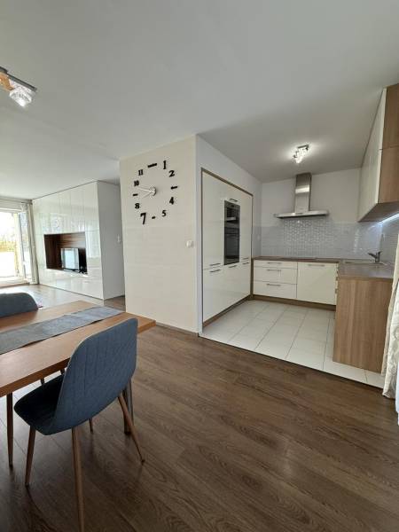 Novinka: Moderný  4-izb. mezonetový byt s balkónom a terasou. Muškát - Jedálenský priestor v 4-izbovom byte s podlahou s dreveným dekorom a kuchyňou v pozadí.