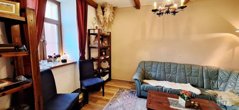 NA PRENÁJOM – odstúpenie vinotéky v srdci Starého Mesta s dušou vína - Obchodné priestory so zelenou sedačkou, poličkami a podlahou s dreveným dekorom.