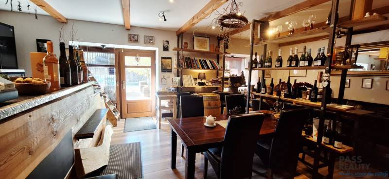 NA PRENÁJOM – odstúpenie vinotéky v srdci Starého Mesta s dušou vína - Interiér obchodných priestorov s barom, stolom a vínnymi policami, podlaha s dreveným dekorom.