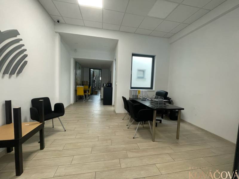 Na prenájom komerčné priestory v priemyselnej zóne v Trenčíne - Obchodné priestory s podlahou s dreveným dekorom, minimalistický nábytok a výrazné stoličky.