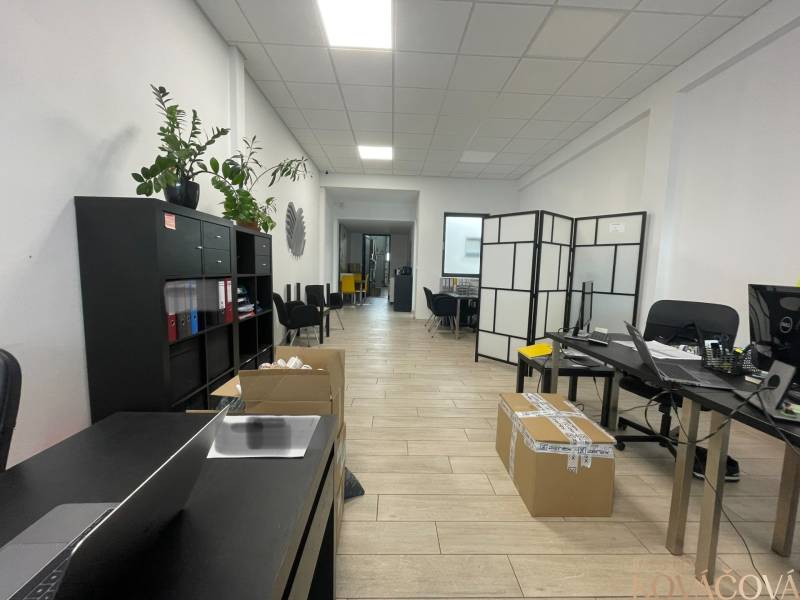 Na prenájom komerčné priestory v priemyselnej zóne v Trenčíne - Obchodné priestory s poličkou, stolmi, kreslami a podlahou s dreveným dekorom.