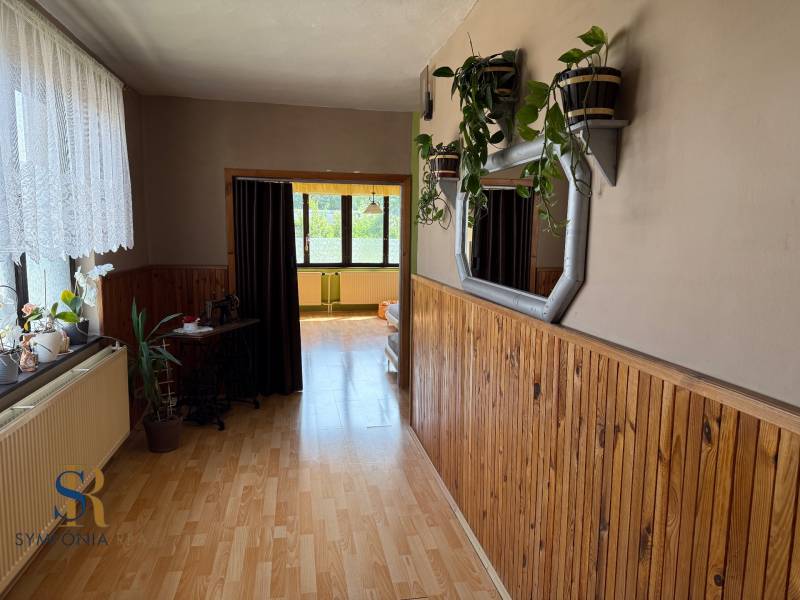 5-izbový rodinný dom v Borskom Mikuláši - bez rezervačej zálohy - Chodba v rodinnom dome s dreveným obložením, podlaha s dreveným dekorom, zeleň.