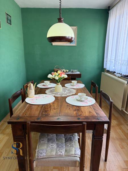 5-izbový rodinný dom v Borskom Mikuláši - bez rezervačej zálohy - Jedáleň v rodinnom dome s dreveným stolom, zelenou stenou a dekoráciami.