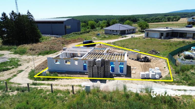 5-izbový dom 162m2 + pozemok 604m2 | Trenčianske Jastrabie - Stavba rodinného domu v Trenčianskom Jastrabí, obklopená zeleňou a ďalšími budovami.