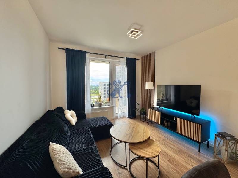 Nový 2-izbový byt na prenájom - Bory - Obývacia izba v 2-izbovom byte s čiernou sedačkou, stolíkmi a podlahou s dreveným dekorom.