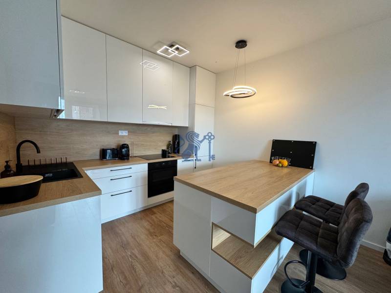 Nový 2-izbový byt na prenájom - Bory - Kuchyňa v 2-izbovom byte s podlahou s dreveným dekorom a barovými stoličkami.