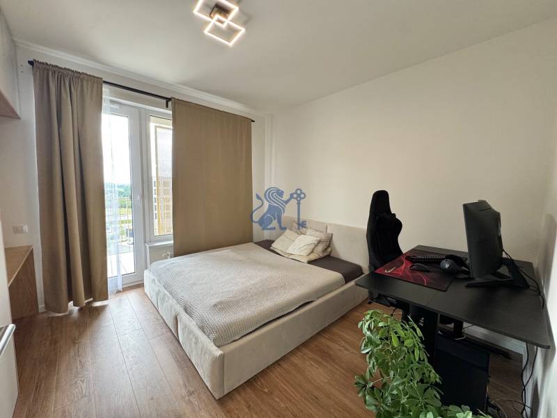 Nový 2-izbový byt na prenájom - Bory - Spálňa v 2-izbovom byte s posteľou, počítačovým stolom a podlahou s dreveným dekorom.