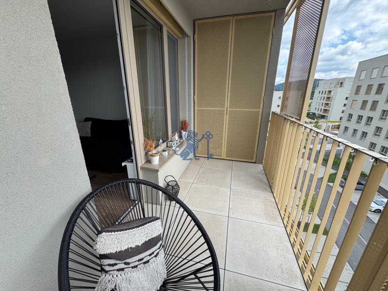 Nový 2-izbový byt na prenájom - Bory - Balkón s kreslom a výhľadom na ulice Michala Bučiča a okolitú zástavbu v Bratislave.