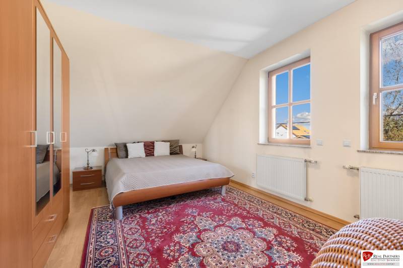 Predaj luxusná 5 izbová Vila,440 m2,pozemok 1061m2,garáž,bazén. - Spálňa s kobercovým vzorom, dreveným nábytkom, veľkými oknami vo vile na ulici Hrušovská.