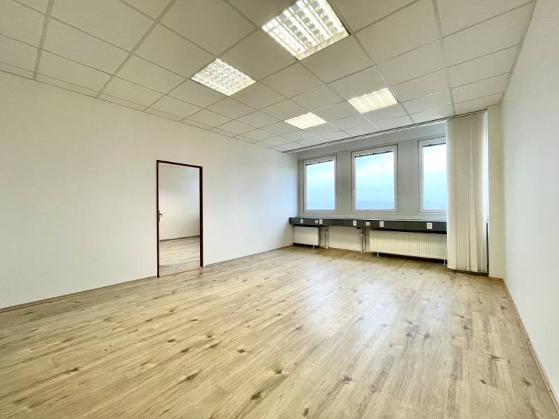 PRIESTORY, NA PRENÁJOM, CENTRUM TRENČÍN, ul. Jilemnického - Kancelária s podlahou s dreveným dekorom a veľkými oknami, neutrálne farby.