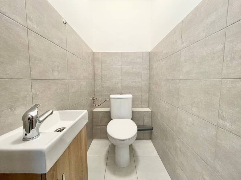 PRIESTORY, NA PRENÁJOM, CENTRUM TRENČÍN, ul. Jilemnického - Toaleta so sivými obkladmi a umývadlom v Kancelárii.