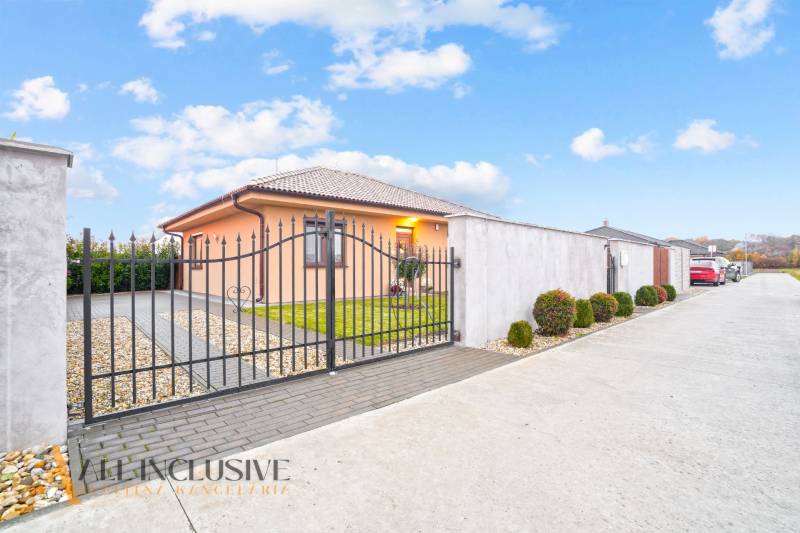 NA PREDAJ MODERNÝ 3-IZB. RD TYPU BUNGALOV V GABČÍKOVE - Rodinný dom v Gabčíkove s kovanou bránou, upravenou záhradou a parkovacou plochou.