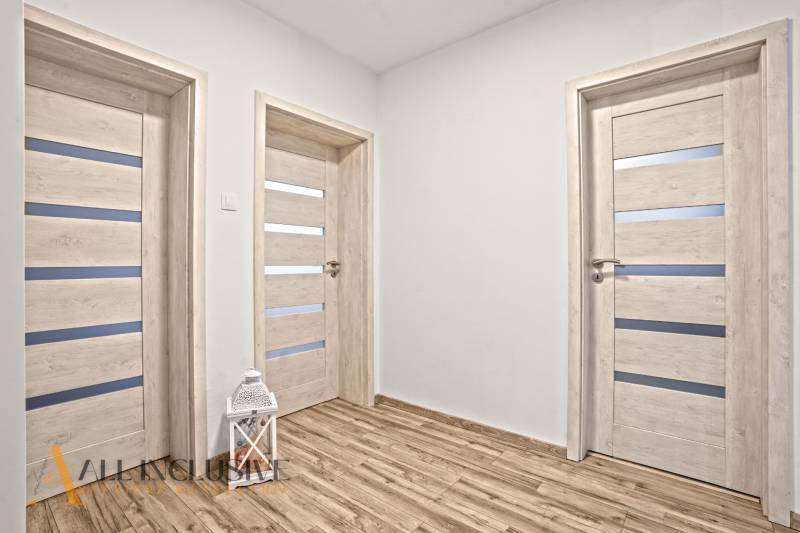 NA PREDAJ MODERNÝ 3-IZB. RD TYPU BUNGALOV V GABČÍKOVE - Interiér rodinného domu s podlahou s dreveným dekorom a bielymi dverami.