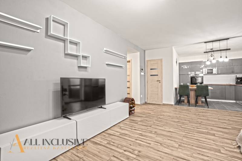 NA PREDAJ MODERNÝ 3-IZB. RD TYPU BUNGALOV V GABČÍKOVE - Obývacia izba v rodinnom dome s podlahou s dreveným dekorom, televízorom, jedálenským stolom a kuchyňou.