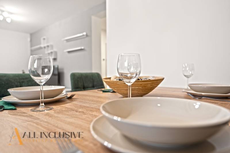 NA PREDAJ MODERNÝ 3-IZB. RD TYPU BUNGALOV V GABČÍKOVE - Jedálenský stôl s pohármi, taniermi a miskou v interiéri rodinného domu.