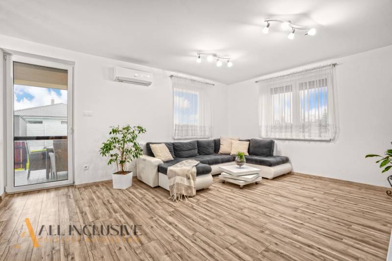 NA PREDAJ MODERNÝ 3-IZB. RD TYPU BUNGALOV V GABČÍKOVE - Obývačka v rodinnom dome s rohovou sedačkou a podlahou s dreveným dekorom.