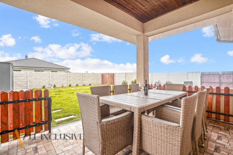 NA PREDAJ MODERNÝ 3-IZB. RD TYPU BUNGALOV V GABČÍKOVE - Terasa rodinného domu v Gabčíkove s ratanovým nábytkom a výhľadom na záhradu.