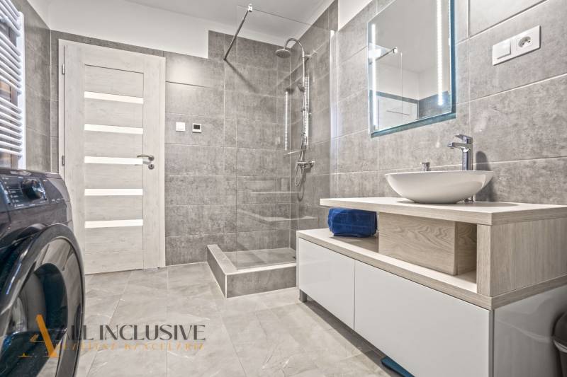 NA PREDAJ MODERNÝ 3-IZB. RD TYPU BUNGALOV V GABČÍKOVE - Kúpeľňa so sprchou, umývadlom na drevenej doske a práčkou v rodinnom dome.