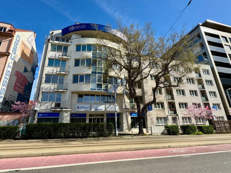 Obchodno- kancelársky priestor s výkladom na Nám. slobody - Na ulici Námestie slobody obchodné priestory v budove s kanceláriami a stromami.