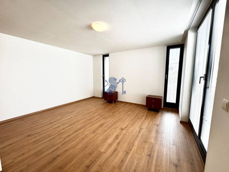 Na prenájom veľký 2- izb. byt na začiatku Koliby s terasou a wellness - Izba v 2-izbovom byte s drevenou podlahou, bielymi stenami a oknami.