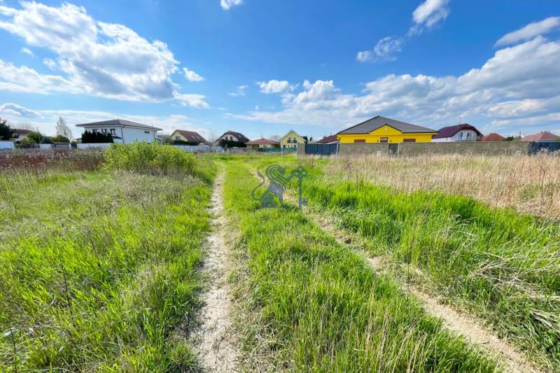 Stavebný pozemok v Bernolákove, Višňová ulica - Pozemok na ulici Višňová s domami v pozadí, ideálny pre bývanie.