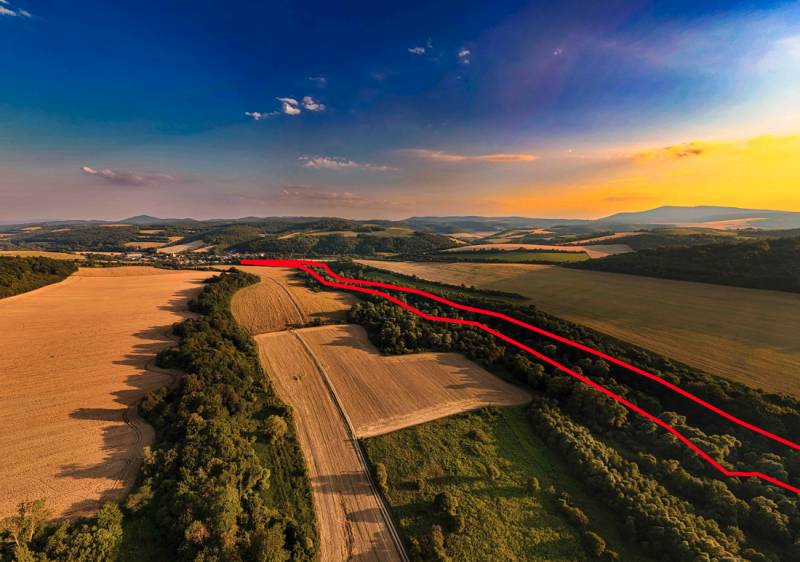 Rokycany – 38.000 m2 LESNÝ POZEMOK v podiele 1/1 - Poľnohospodárske a lesné pozemky v Rokycanoch pri západe slnka, s viditeľnou červenou čiarou.