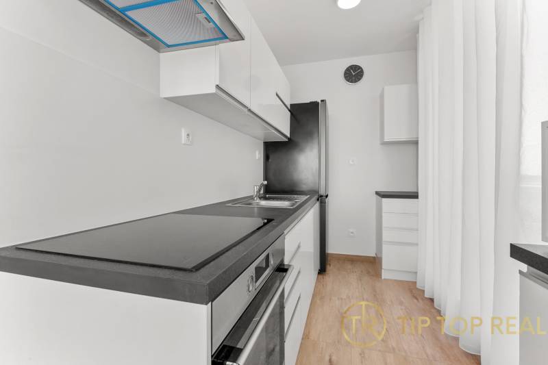 OPAL - NOVÝ a KOMPLETNE ZARIADENÝ 2,5-izbový byt s LODŽIOU a PARKOVANÍ - Svetlá kuchyňa s podlahou s dreveným dekorom v 2-izbovom byte, vybavená spotrebičmi.