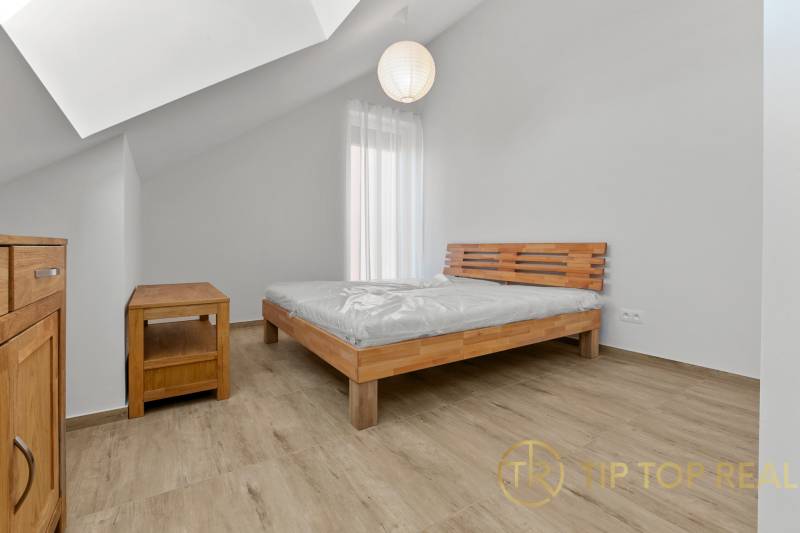 OPAL - NOVÝ a KOMPLETNE ZARIADENÝ 2,5-izbový byt s LODŽIOU a PARKOVANÍ - Spálňa v 2-izbovom byte s posteľou, dreveným nábytkom a podlahou s dreveným dekorom.