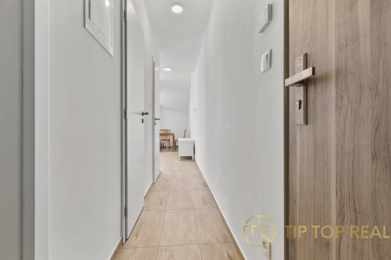 OPAL - NOVÝ a KOMPLETNE ZARIADENÝ 2,5-izbový byt s LODŽIOU a PARKOVANÍ - Chodba s podlahou s dreveným dekorom vedie k jedálenskému kútu v 2-izbovom byte.