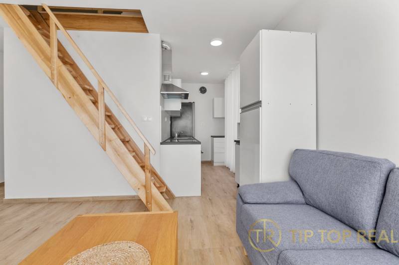 OPAL - NOVÝ a KOMPLETNE ZARIADENÝ 2,5-izbový byt s LODŽIOU a PARKOVANÍ - Obývacia izba v 2-izbovom byte s gaučom, dreveným schodiskom a kuchyňou.