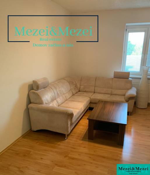 Na predaj útulný 2-izbový byt, Bratislava – Nové Mesto - Obývacia izba v 2-izbovom byte s rohovou sedačkou a stolíkom na podlahe s dreveným dekorom.