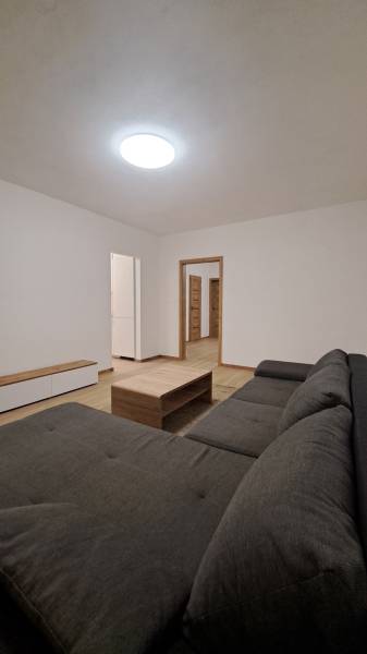 Prenájom 2 izbového bytu v novostavbe, Dubnica nad Váhom, 66 m2 - Obývacia izba s pohodlnou sedačkou, dreveným stolíkom a podlahou s dreveným dekorom.