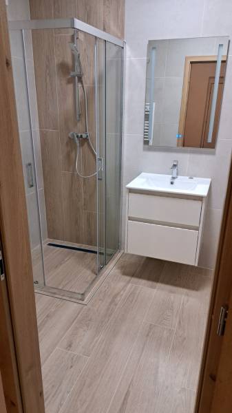 Prenájom 2 izbového bytu v novostavbe, Dubnica nad Váhom, 66 m2 - Kúpeľňa s podlahou s dreveným dekorom, sprchovým kútom a umývadlom v 2-izbovom byte.