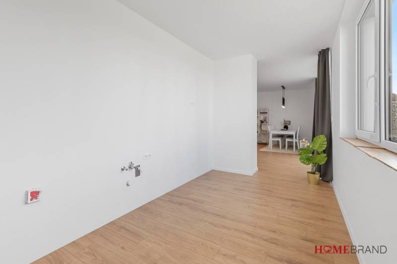 BÝVANIE VO VILA DOME - POSLEDNÝ VOĽNÝ 3-IZBOVÝ BYT SO ZÁHRADOU - Izba v 3-izbovom byte s podlahou s dreveným dekorom a stolom na opačnej strane.