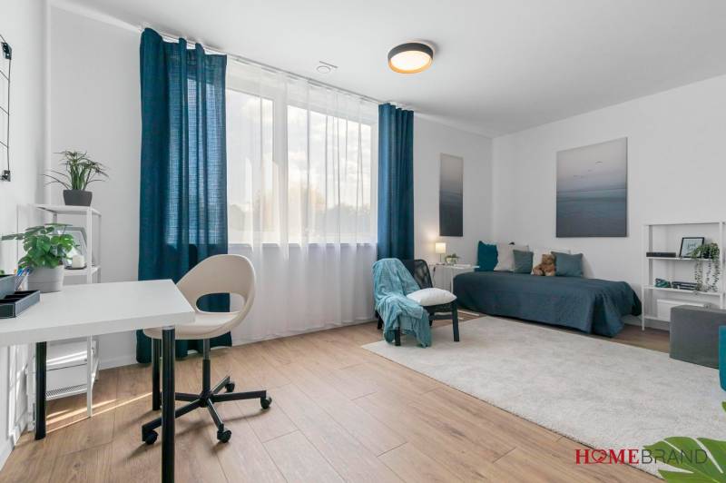 BÝVANIE VO VILA DOME - POSLEDNÝ VOĽNÝ 3-IZBOVÝ BYT SO ZÁHRADOU - Svetlá izba s pracovným stolom, posteľou a podlahou s dreveným dekorom v 3-izbovom byte.