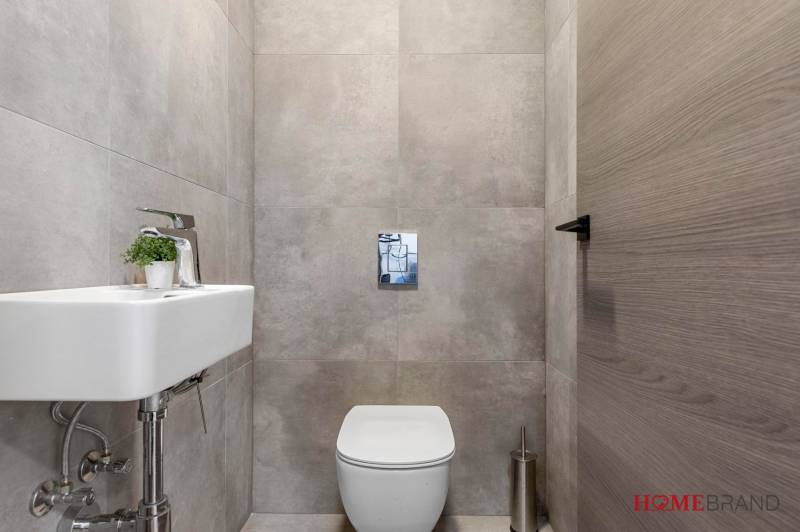 BÝVANIE VO VILA DOME - POSLEDNÝ VOĽNÝ 3-IZBOVÝ BYT SO ZÁHRADOU - Toaleta s umývadlom a sivými obkladmi v 3-izbovom byte.