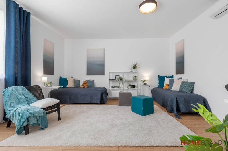 BÝVANIE VO VILA DOME - POSLEDNÝ VOĽNÝ 3-IZBOVÝ BYT SO ZÁHRADOU - Obývacia izba s dvomi posteľami, podlaha s dreveným dekorom, koberec, dekorácie a nábytok.