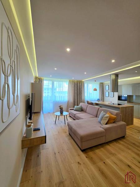 REZERVOVANÉ - 3i, OV, 71m2 + loggia, Lomonosovova, dizajnový, zariaden - Obývačka v 3-izbovom byte s pohovkou, podlahou s dreveným dekorom a moderným osvetlením.