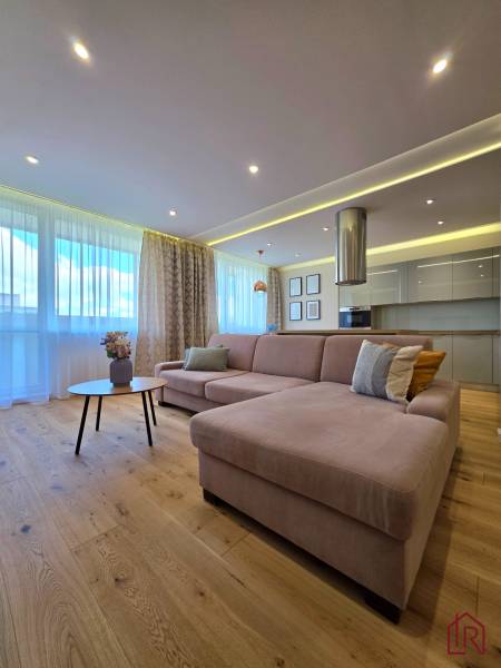 REZERVOVANÉ - 3i, OV, 71m2 + loggia, Lomonosovova, dizajnový, zariaden - Obývačka 3-izbového bytu s rohovou sedačkou, podlahou s dreveným dekorom a vkusnými dekoráciami.