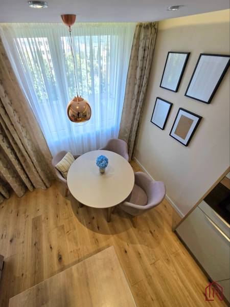REZERVOVANÉ - 3i, OV, 71m2 + loggia, Lomonosovova, dizajnový, zariaden - Jedálenský kút s okrúhlym stolom, kreslami a podlahou s dreveným dekorom v 3-izbovom byte.