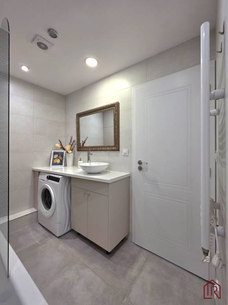 REZERVOVANÉ - 3i, OV, 71m2 + loggia, Lomonosovova, dizajnový, zariaden - Kúpeľňa v 3-izbovom byte s umývadlom, práčkou, zrkadlom a dekoráciou na skrinke.