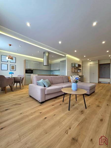 REZERVOVANÉ - 3i, OV, 71m2 + loggia, Lomonosovova, dizajnový, zariaden - Obývacia izba s podlahou s dreveným dekorom, sedacou súpravou a jedálenským stolom v 3-izbovom byte.