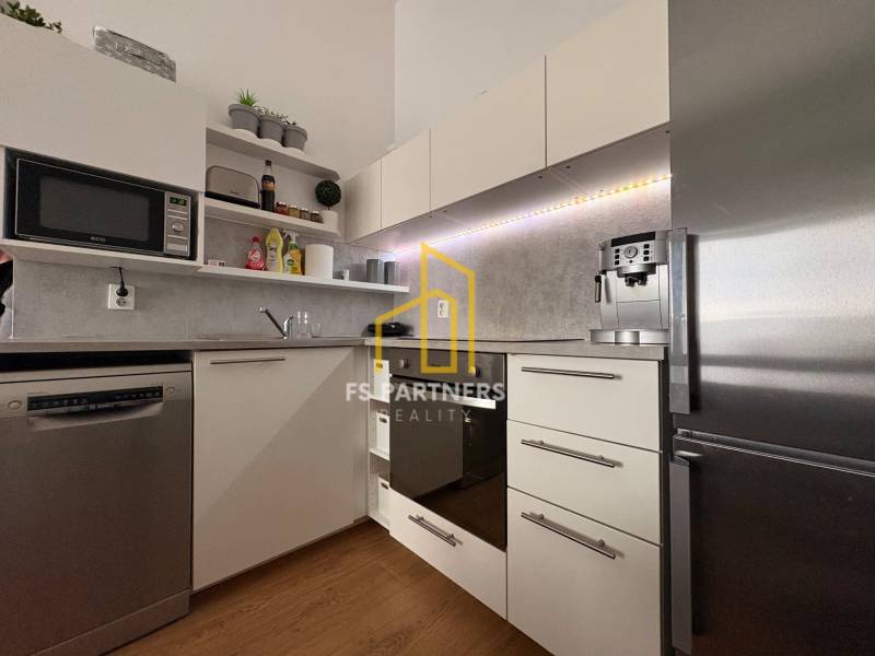 Prenájom moderného 2-izbového bytu v centre Komárna, 40 m² – Petőfiho  - Kuchyňa v 2-izbovom byte s podlahou s dreveným dekorom a modernými spotrebičmi.