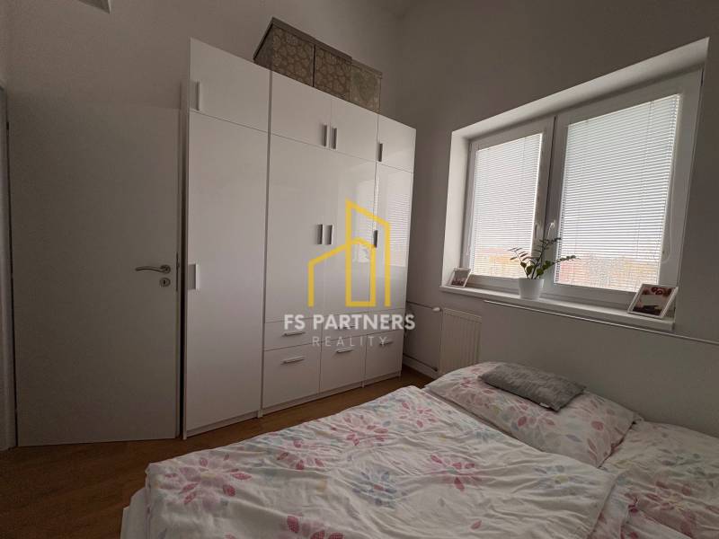 Prenájom moderného 2-izbového bytu v centre Komárna, 40 m² – Petőfiho  - Spálňa v 2-izbovom byte s podlahou s dreveným dekorom a veľkou skriňou.