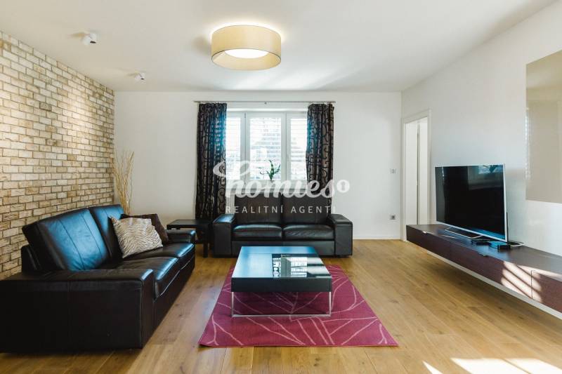 PREDAJ  kompletne prerobený 3 izbový rodinný dom, Nitra - centrum - Obývačka s koženou sedačkou, tehlovou stenou a podlahou s dreveným dekorom v rodinnom dome.