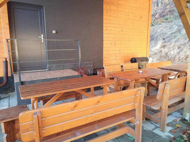 NOVOSTAVBA: 6-izbová CHATA, VL pozemok 484 m2 v Martine  - Chata na Stráňach v Martine s drevenými lavicami a grilom na terase.