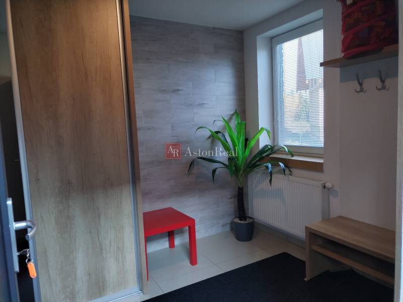 NOVOSTAVBA: 6-izbová CHATA, VL pozemok 484 m2 v Martine  - Interiér chaty s červeným stolíkom, rastlinou, radiátorom a stenou s dreveným dekorom.