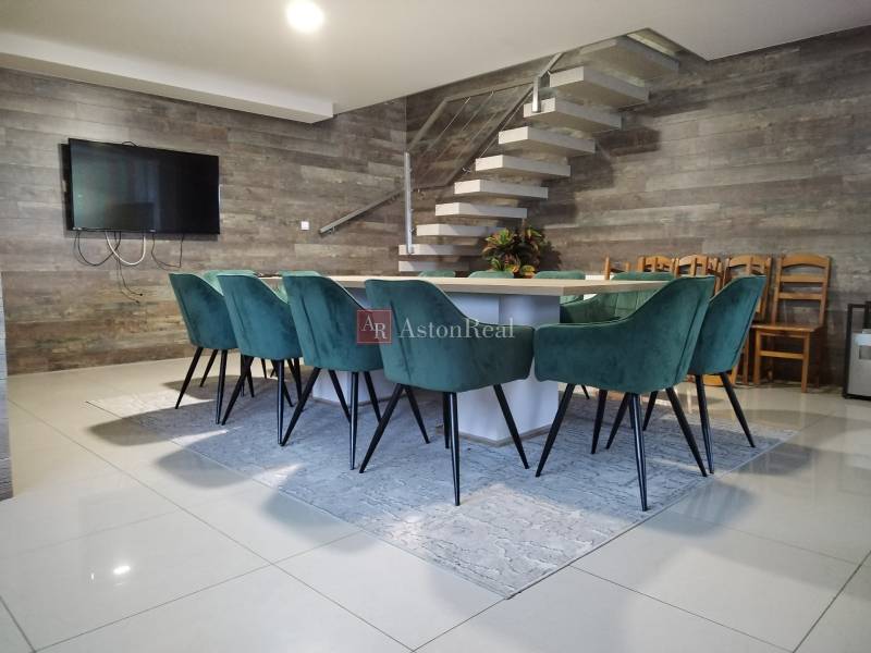 NOVOSTAVBA: 6-izbová CHATA, VL pozemok 484 m2 v Martine  - Jedálenský stôl s tyrkysovými stoličkami na chatovej podlahe s dreveným dekorom.